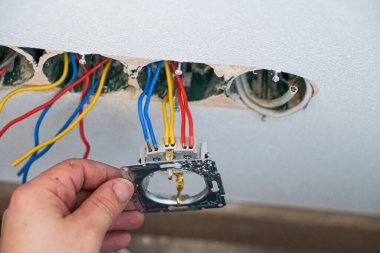 Alçıtaşı duvarına soket takan elektrikçinin elleri