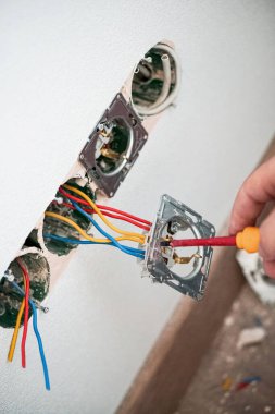 Alçıtaşı duvarına soket takan elektrikçinin elleri