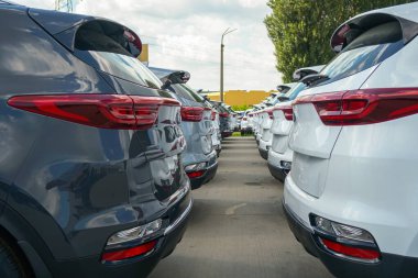 New cars stand in the parking lot of the warehouse, view from the front of the cars