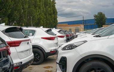 New cars stand in the parking lot of the warehouse, view from the front of the cars