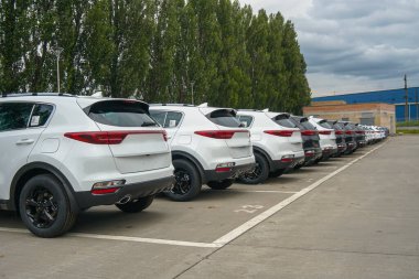 New cars stand in the parking lot of the warehouse, view from the rear of the cars