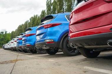 New cars stand in the parking lot of the warehouse, view from the rear of the cars