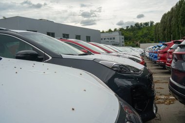 New cars stand in the parking lot of the warehouse, view from the front of the cars