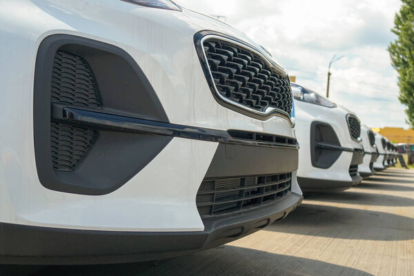 New cars stand in the parking lot of the warehouse, view from the front of the cars