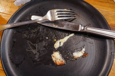 Ahşap arka planda yemek artıkları ve çatal ile kirli plaka, üst görünüm