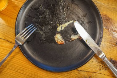 Ahşap arka planda yemek artıkları ve çatal ile kirli plaka, üst görünüm