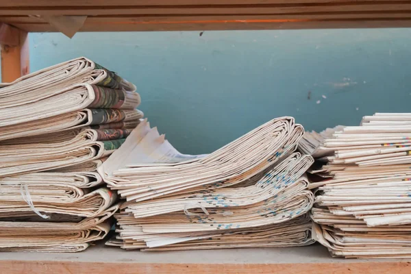 杭の角の近くに古い新聞のきちんとした山 ストックフォト