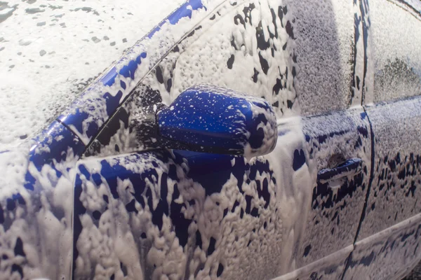 Myjnia samochodowa z płynącą wodą i pianką. — Zdjęcie stockowe