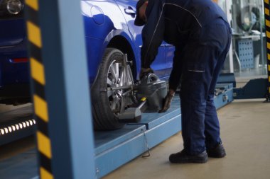 Tekerlekler hizalama kamber için gezici sensörleri ile stand arabayı kontrol servis istasyonu atölyesinde.