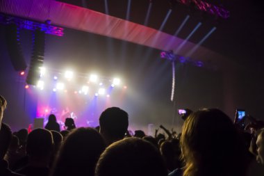 Parlak sahne ışıkları önünde konser kalabalığının siluetleri