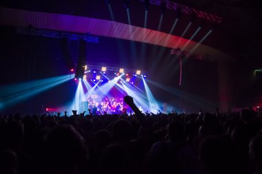 Parlak sahne ışıkları önünde konser kalabalığının siluetleri