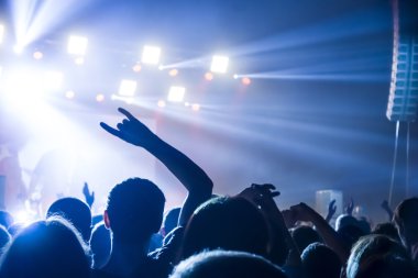 Parlak sahne ışıkları önünde konser kalabalığının siluetleri
