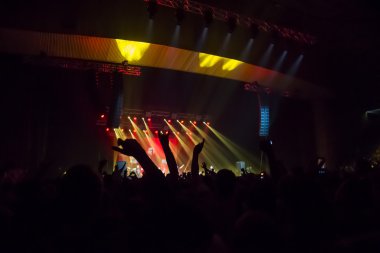 Parlak sahne ışıkları önünde konser kalabalığının siluetleri