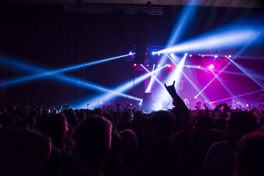 Parlak sahne ışıkları önünde konser kalabalığının siluetleri