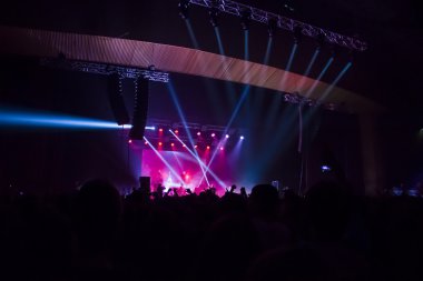 Parlak sahne ışıkları önünde konser kalabalığının siluetleri