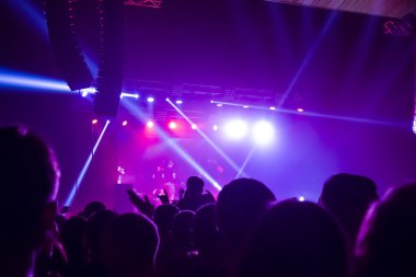 Parlak sahne ışıkları önünde konser kalabalığının siluetleri