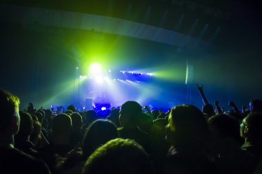 Parlak sahne ışıkları önünde konser kalabalığının siluetleri