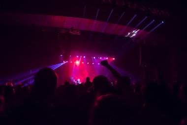 Parlak sahne ışıkları önünde konser kalabalığının siluetleri