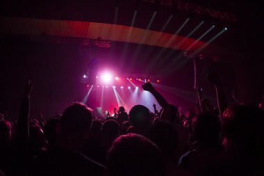 Parlak sahne ışıkları önünde konser kalabalığının siluetleri