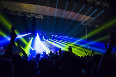 Parlak sahne ışıkları önünde konser kalabalığının siluetleri