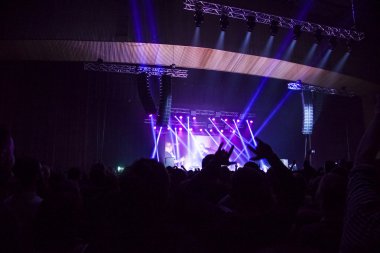 Parlak sahne ışıkları önünde konser kalabalığının siluetleri