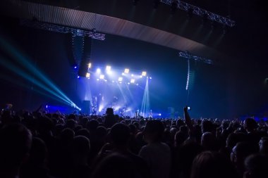 Parlak sahne ışıkları önünde konser kalabalığının siluetleri