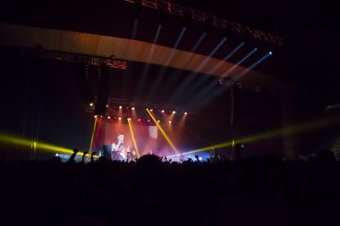 Parlak sahne ışıkları önünde konser kalabalığının siluetleri