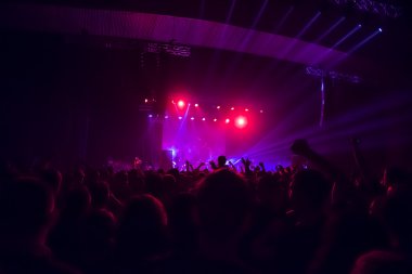 Parlak sahne ışıkları önünde konser kalabalığının siluetleri