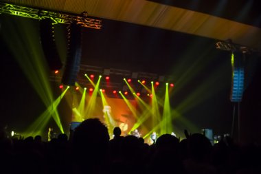 Parlak sahne ışıkları önünde konser kalabalığının siluetleri