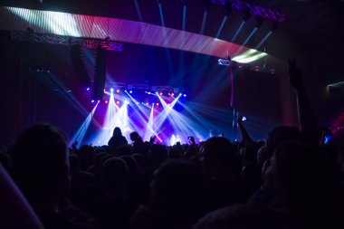 Parlak sahne ışıkları önünde konser kalabalığının siluetleri