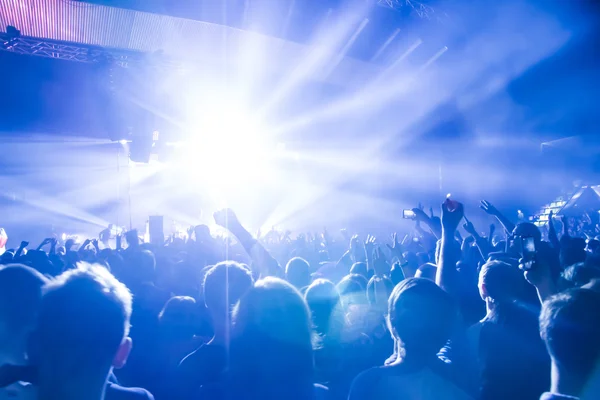Parlak sahne ışıkları önünde konser kalabalığının siluetleri