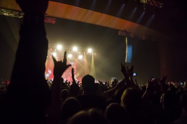 Parlak sahne ışıkları önünde konser kalabalığının siluetleri