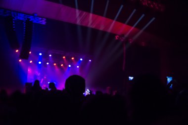 Parlak sahne ışıkları önünde konser kalabalığının siluetleri