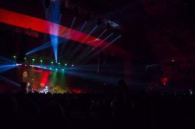 Parlak sahne ışıkları önünde konser kalabalığının siluetleri