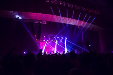 Parlak sahne ışıkları önünde konser kalabalığının siluetleri