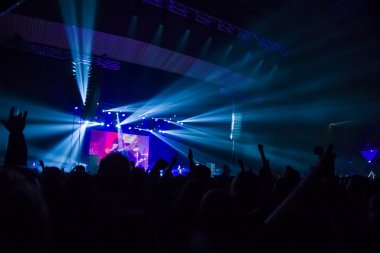 Parlak sahne ışıkları önünde konser kalabalığının siluetleri