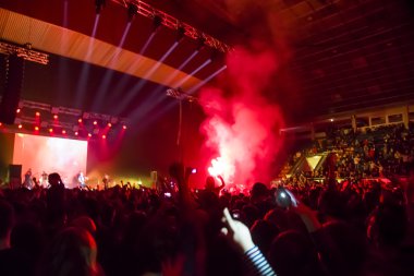 Parlak sahne ışıkları önünde konser kalabalığının siluetleri
