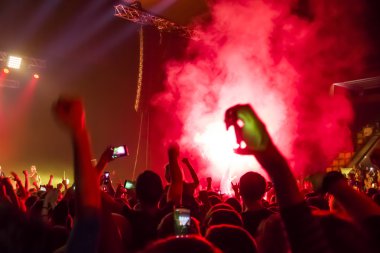 Parlak sahne ışıkları önünde konser kalabalığının siluetleri