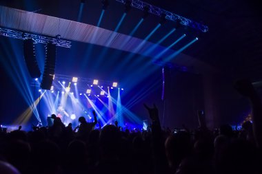Parlak sahne ışıkları önünde konser kalabalığının siluetleri