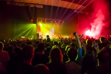 Parlak sahne ışıkları önünde konser kalabalığının siluetleri