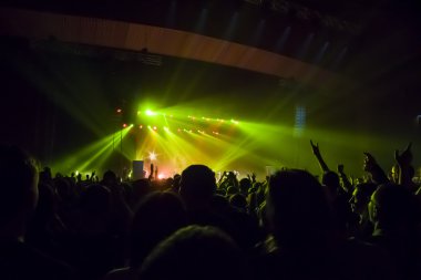 Parlak sahne ışıkları önünde konser kalabalığının siluetleri