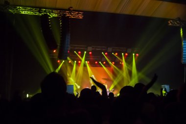 Parlak sahne ışıkları önünde konser kalabalığının siluetleri