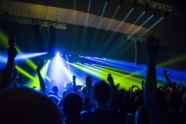 Parlak sahne ışıkları önünde konser kalabalığının siluetleri