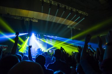 Parlak sahne ışıkları önünde konser kalabalığının siluetleri