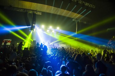 Parlak sahne ışıkları önünde konser kalabalığının siluetleri