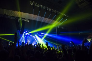 Parlak sahne ışıkları önünde konser kalabalığının siluetleri