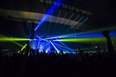 Parlak sahne ışıkları önünde konser kalabalığının siluetleri