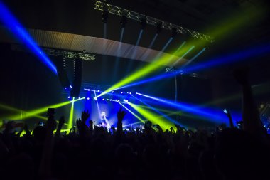 Parlak sahne ışıkları önünde konser kalabalığının siluetleri