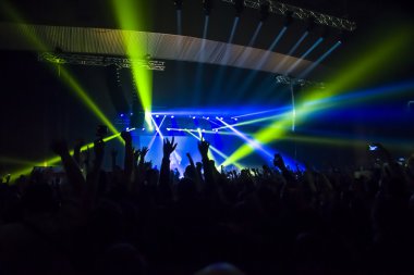 Parlak sahne ışıkları önünde konser kalabalığının siluetleri