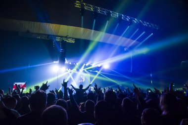 Parlak sahne ışıkları önünde konser kalabalığının siluetleri